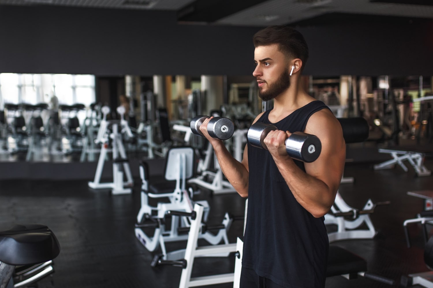 muscular-young-man-working-out-gym-doing-exercises-with-dumbbells-biceps-min
